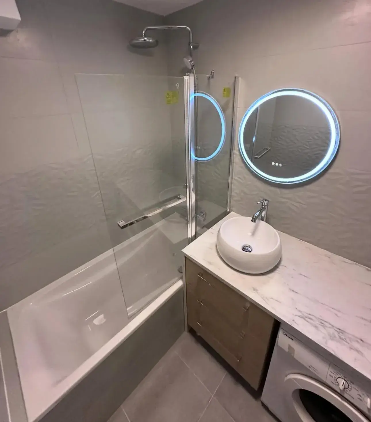 Salle de bains aux tons minéraux avec vasque ronde et miroir lumineux
