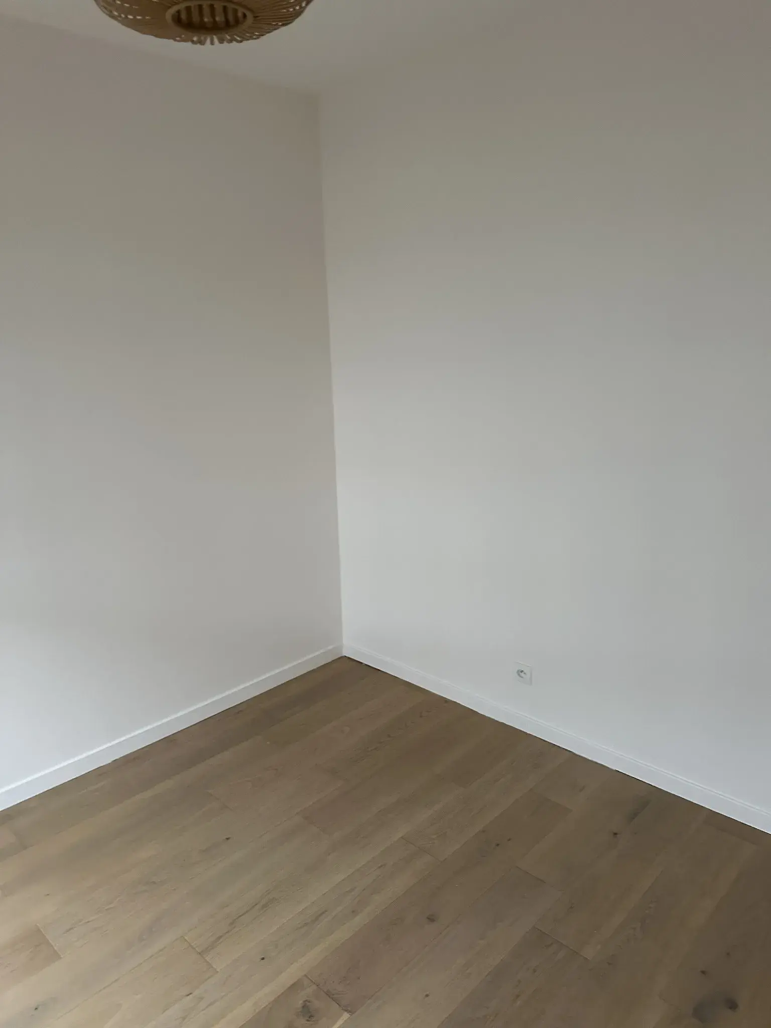 Angle d’une chambre vide après travaux, avec murs blancs et sol clair