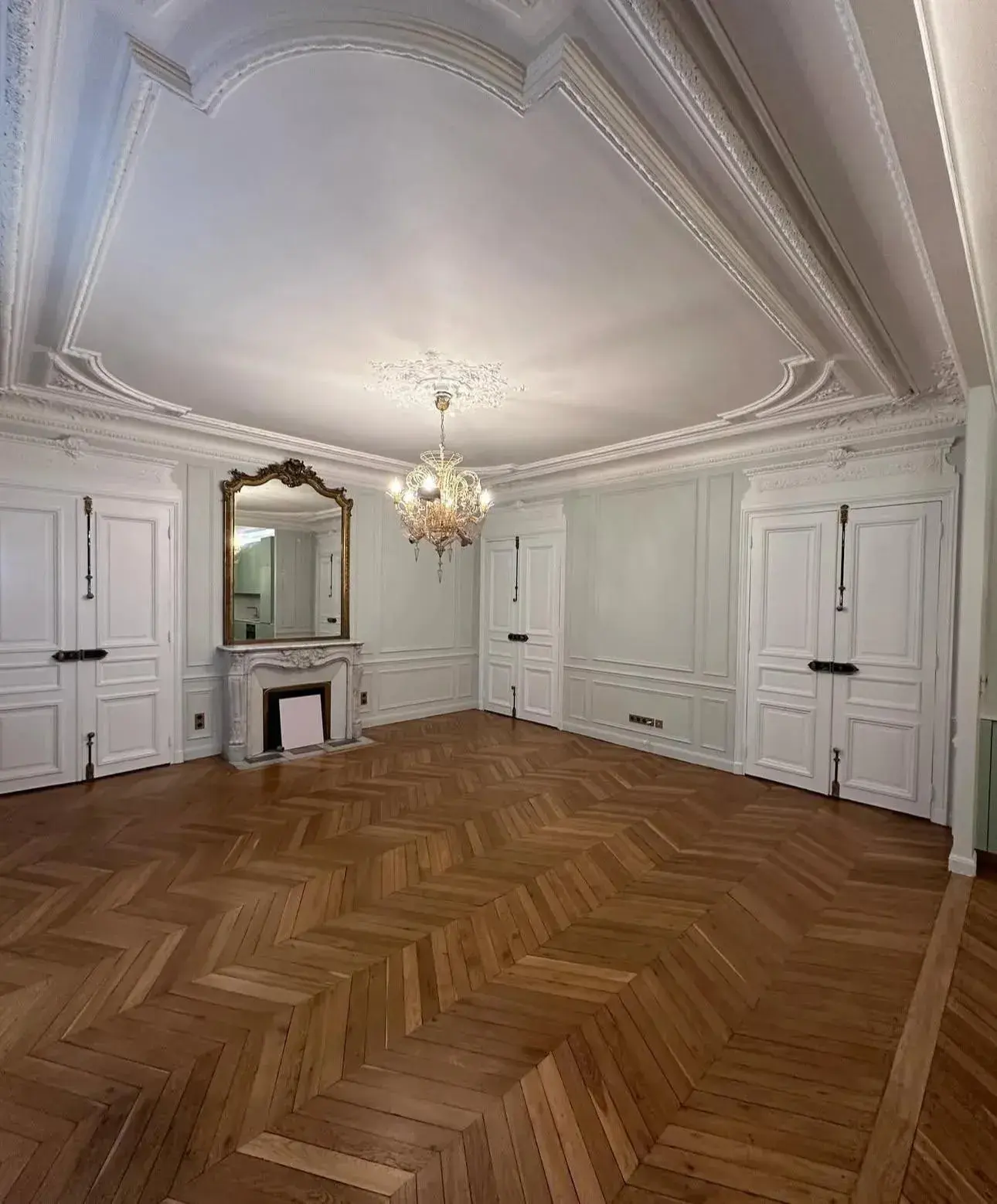 Pièce rénovée avec parquet à chevrons, moulures et cheminée