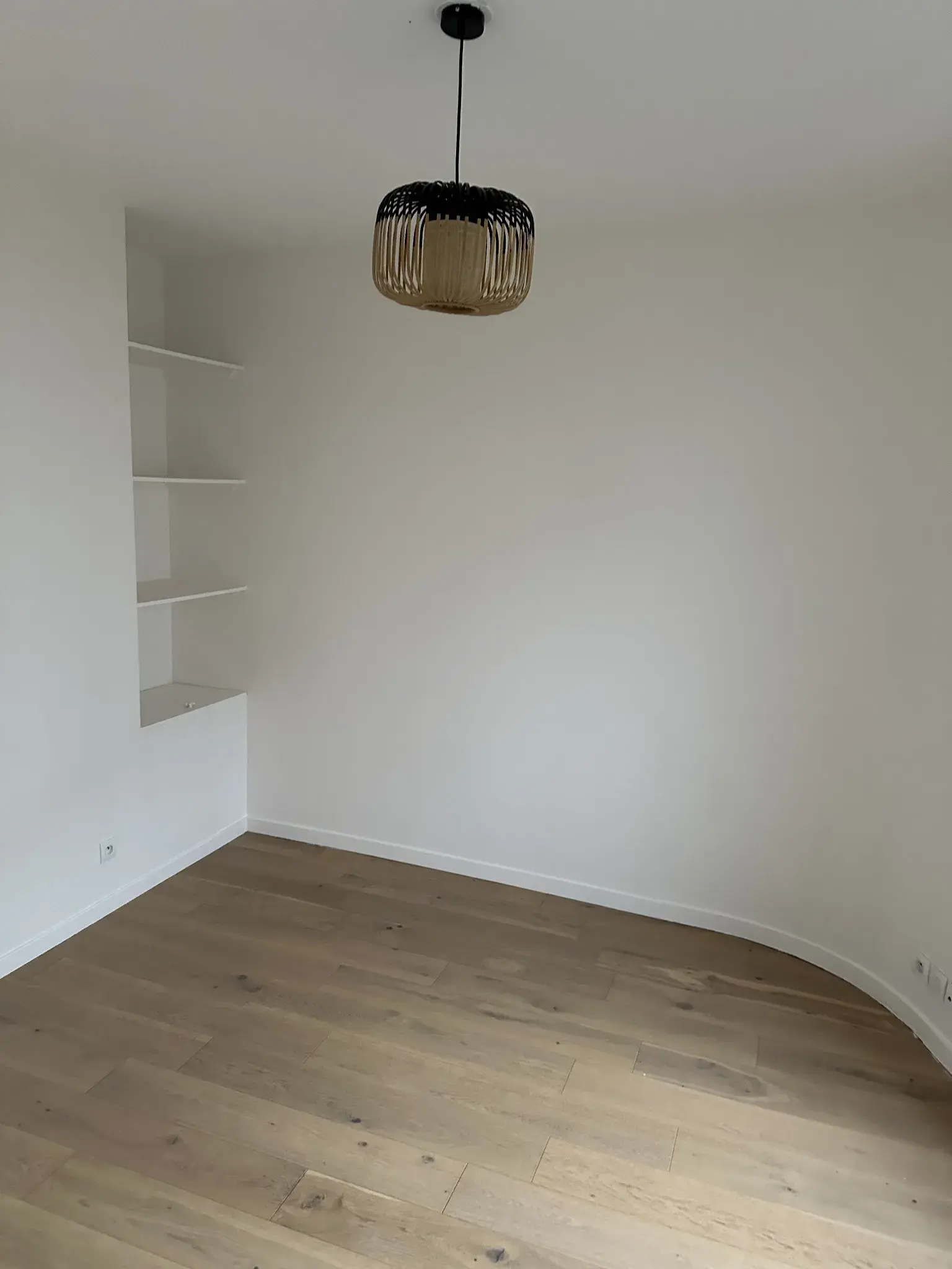 Chambre vide avec murs blancs, étagères et sol clair