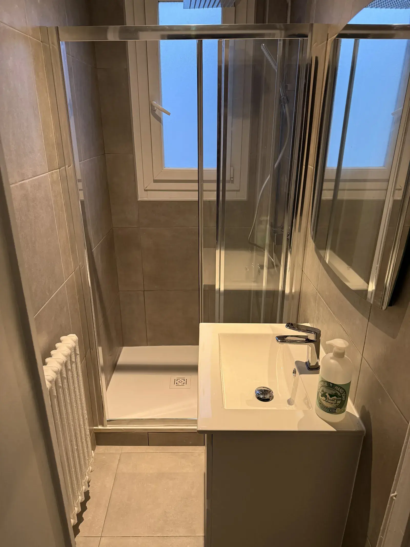 Douche avec receveur blanc et paroi vitrée dans une petite salle d’eau