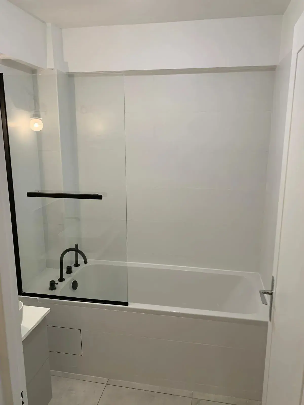 Baignoire blanche, paroi vitrée et revêtements muraux clairs dans une autre réalisation JBY