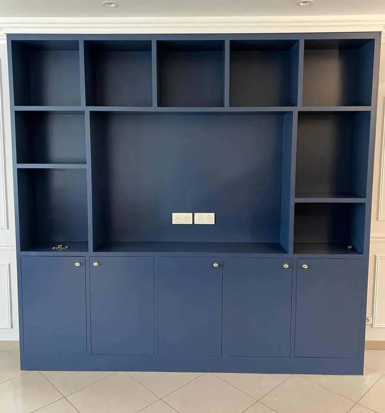 Rangement bleu intégré au mur avec étagères ouvertes et placards bas